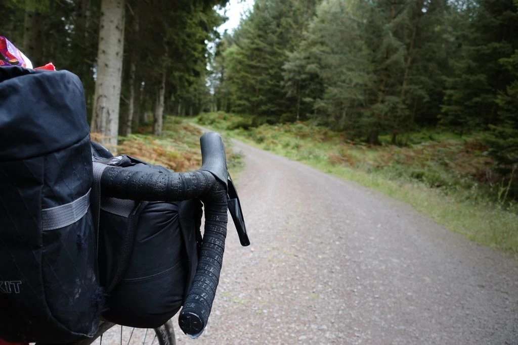 A gravel track snakes away through the trees ahead of my handlebars